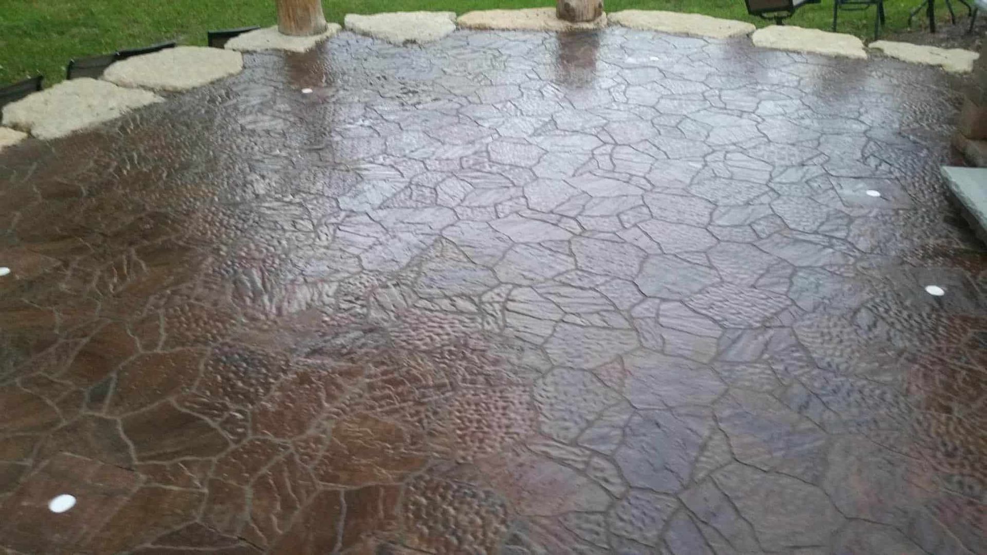 A concrete patio with a circular pattern and a table and chairs in the background.