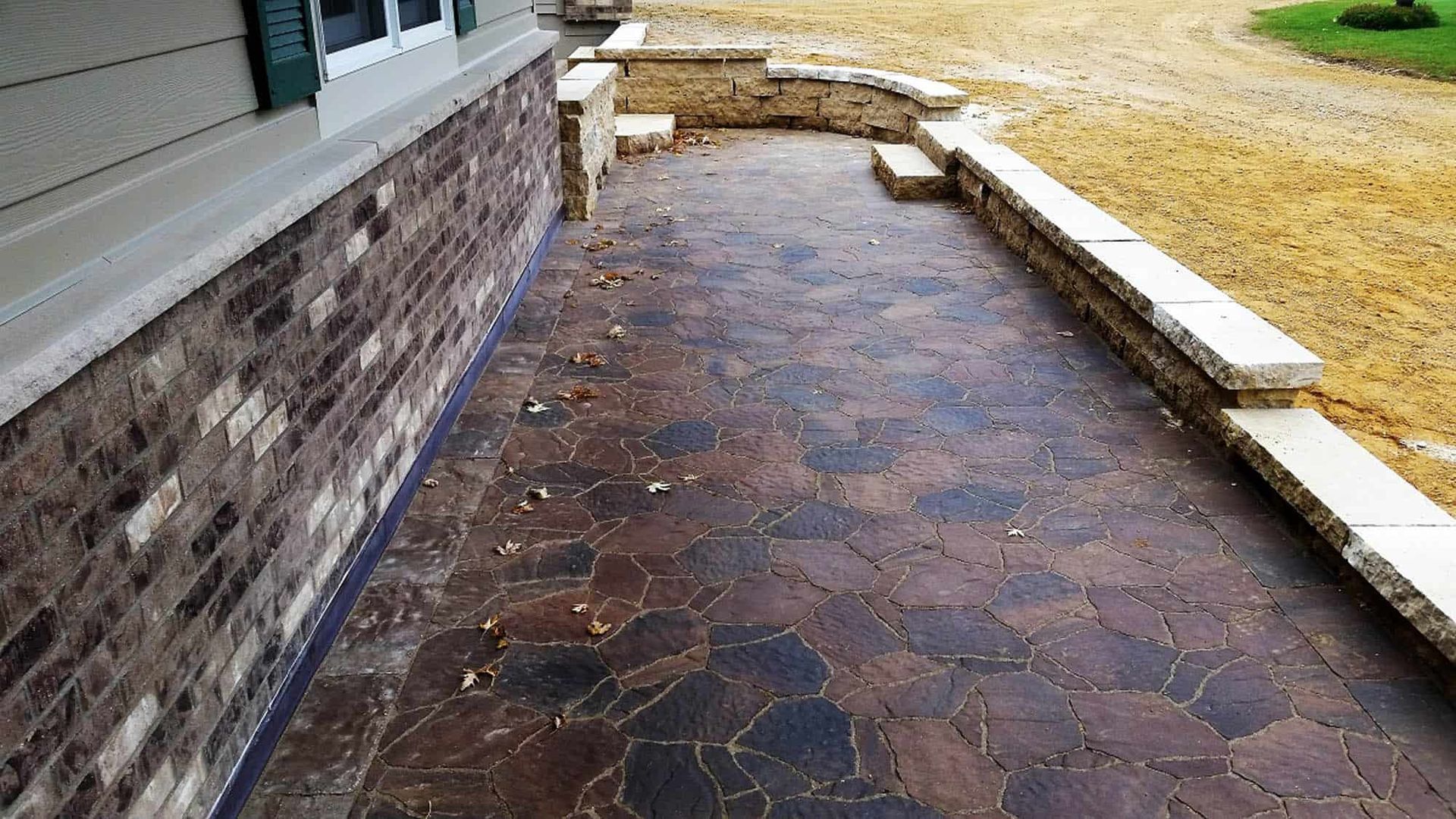 A stone walkway leading to a house with a brick wall