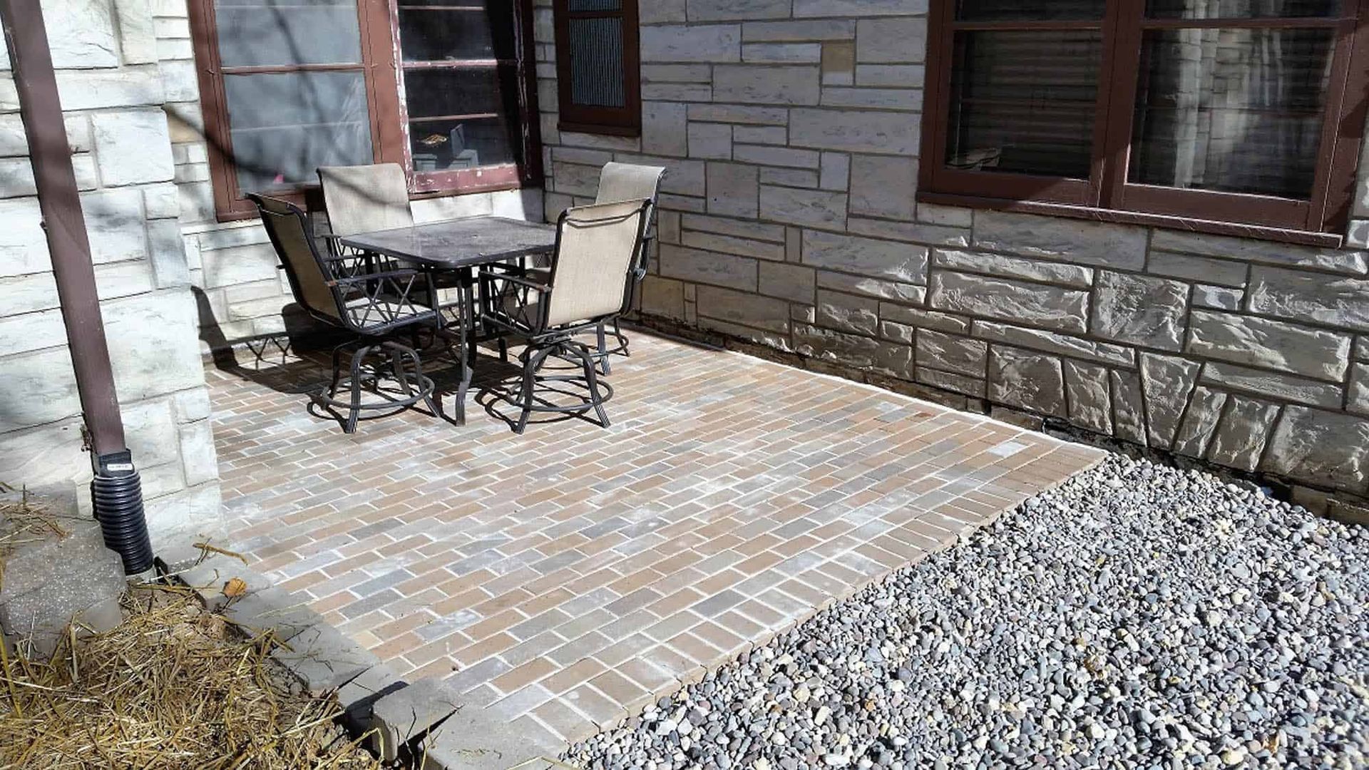 A patio with a table and chairs in front of a brick building