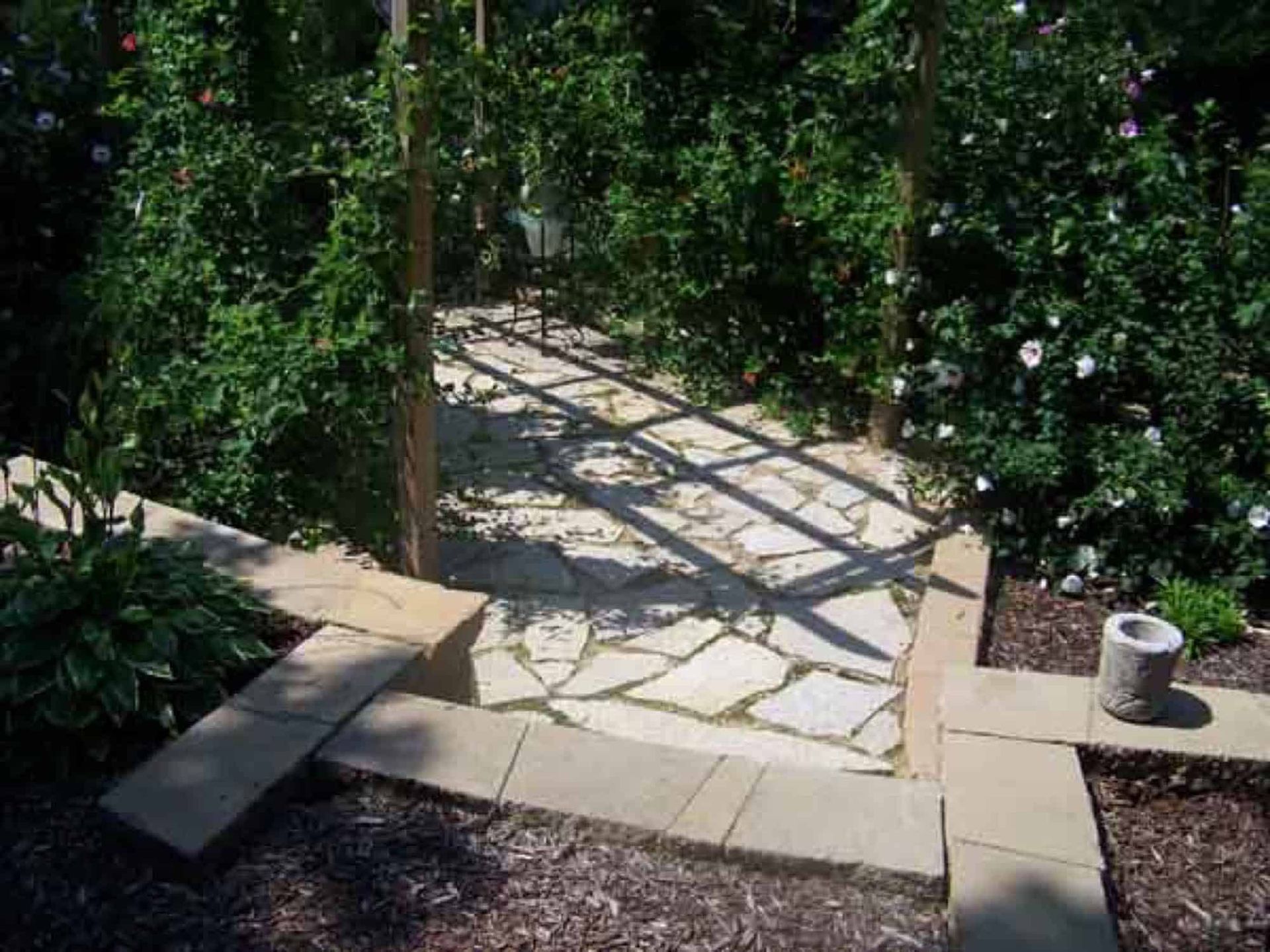 A stone walkway in a garden surrounded by trees