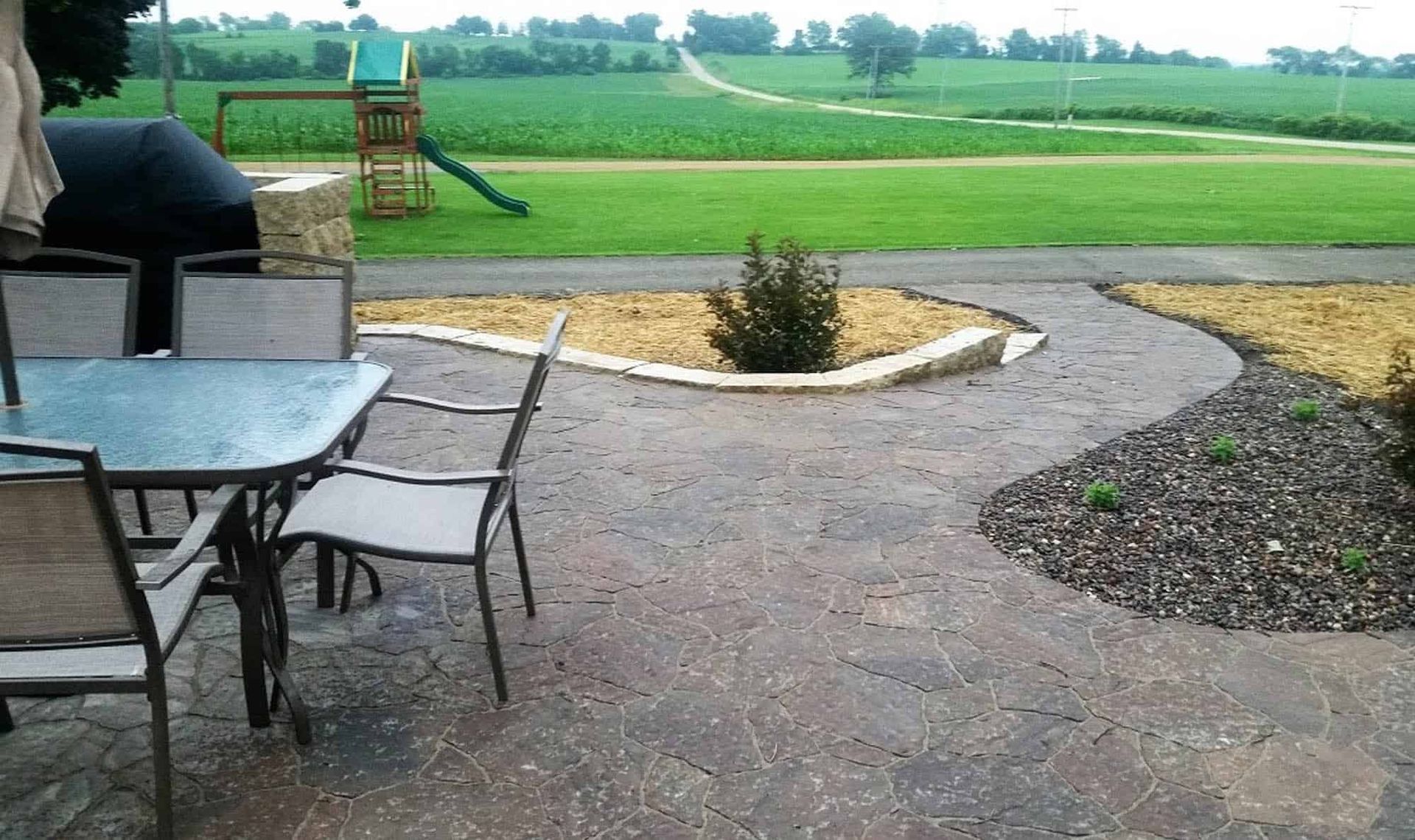 A patio with a table and chairs and a playground in the background