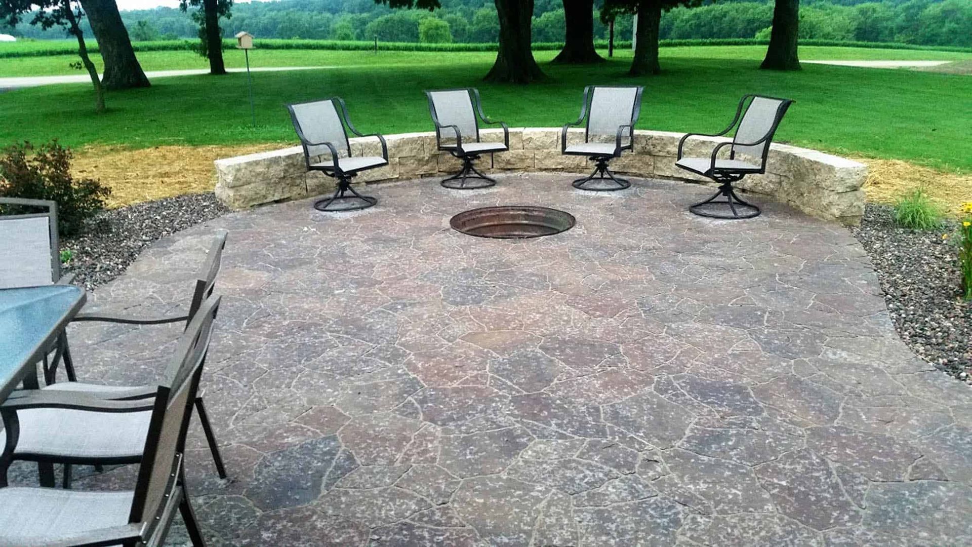 A patio with chairs and a fire pit in the middle