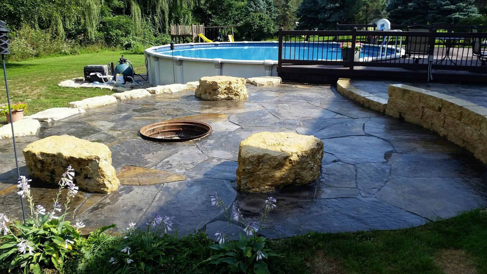 A fire pit in a backyard next to a pool.