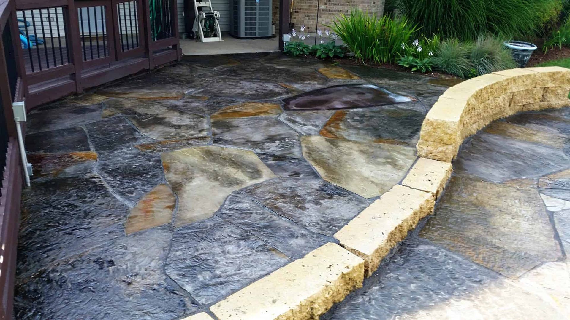 A stone walkway leading to a house with a fence in the background.