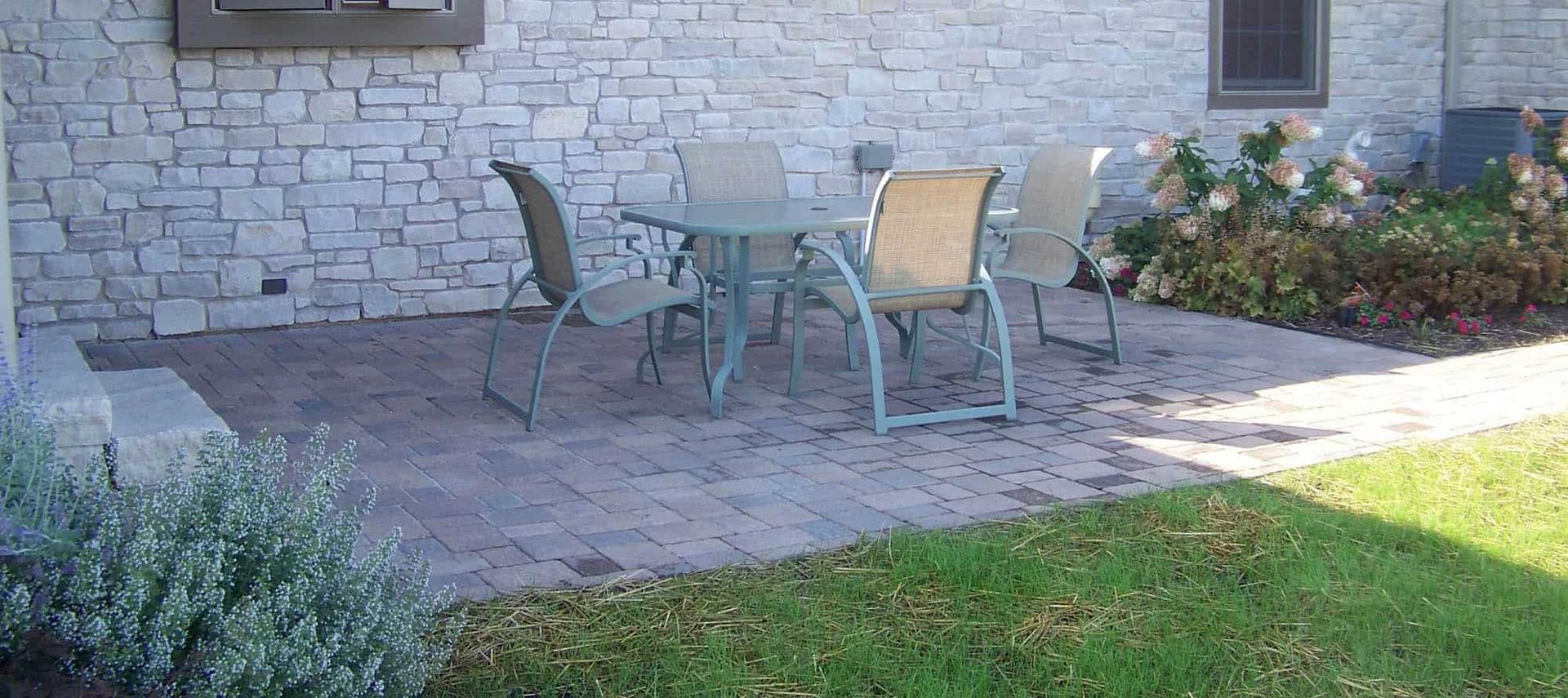 A patio with a table and chairs in front of a brick building