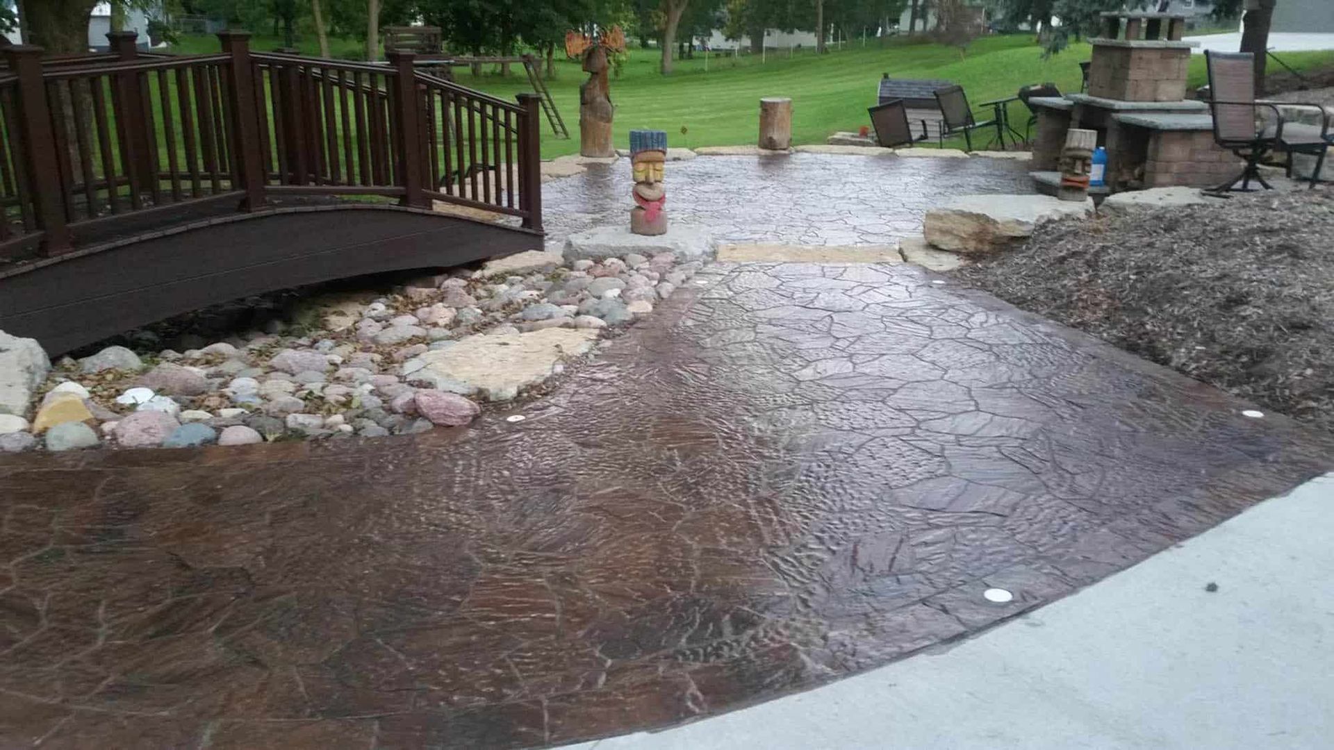 A patio with a wooden bridge and a concrete walkway
