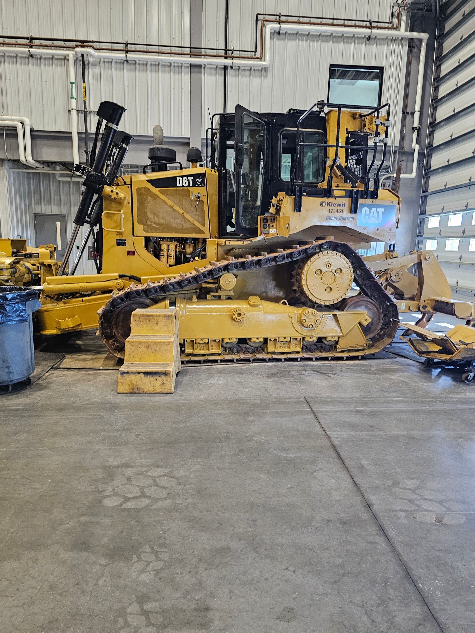 Yellow Caterpillar bulldozer parked inside a large industrial building.