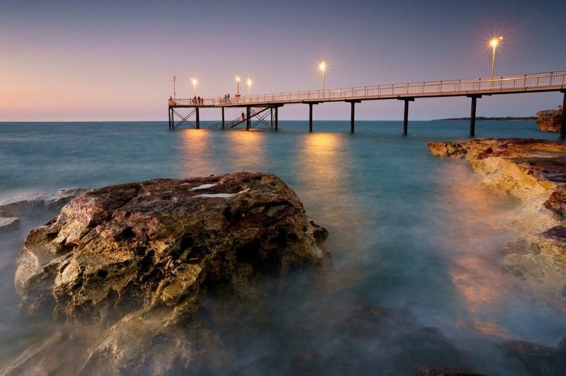 A Pier Overlooking a Body of Water With Rocks in the Foreground — Voyager Trailers in Nightcliff, NT