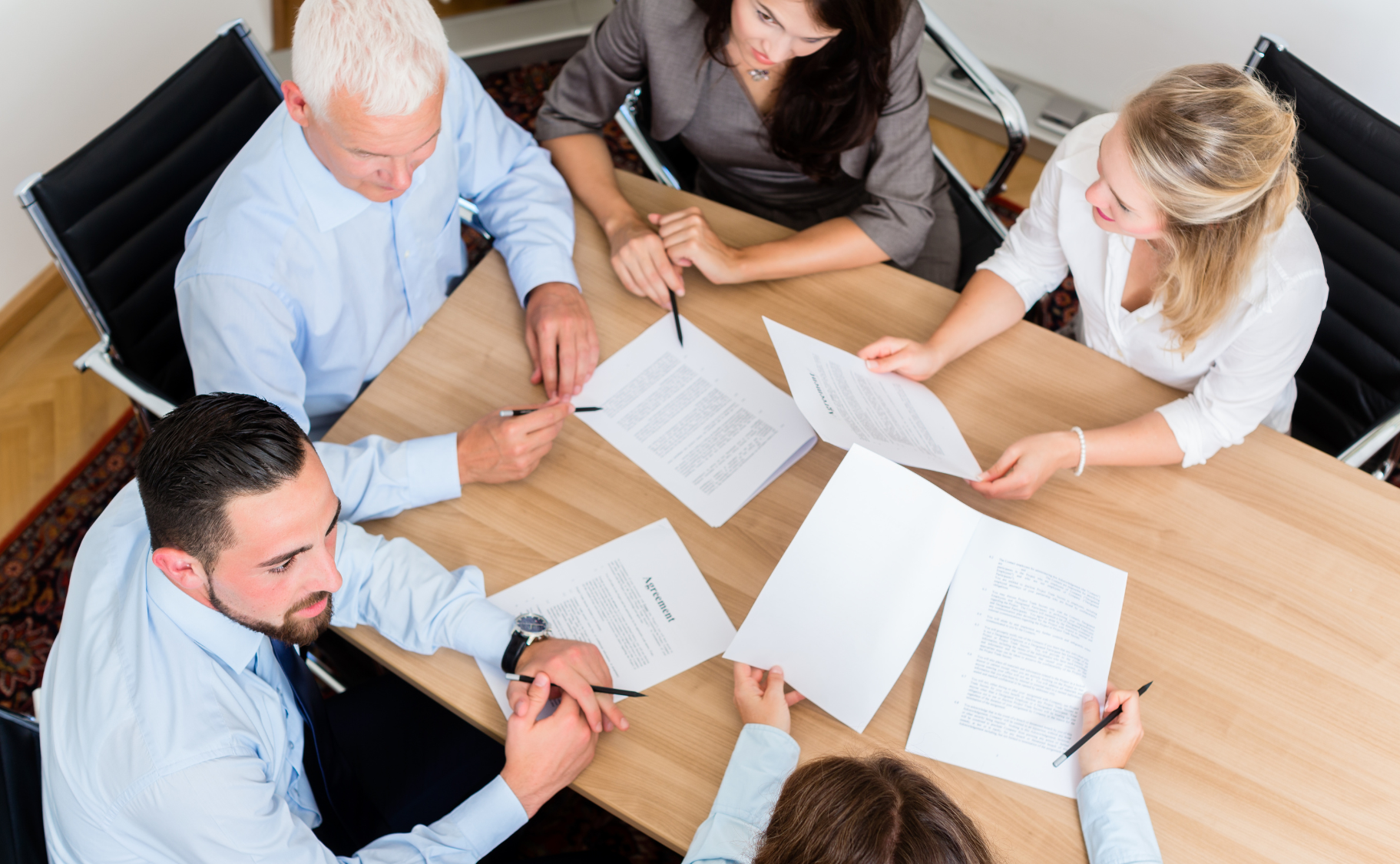 A group of people are sitting around a table looking at papers.