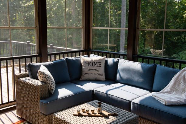 A screened in porch with a blue sectional couch and a coffee table.