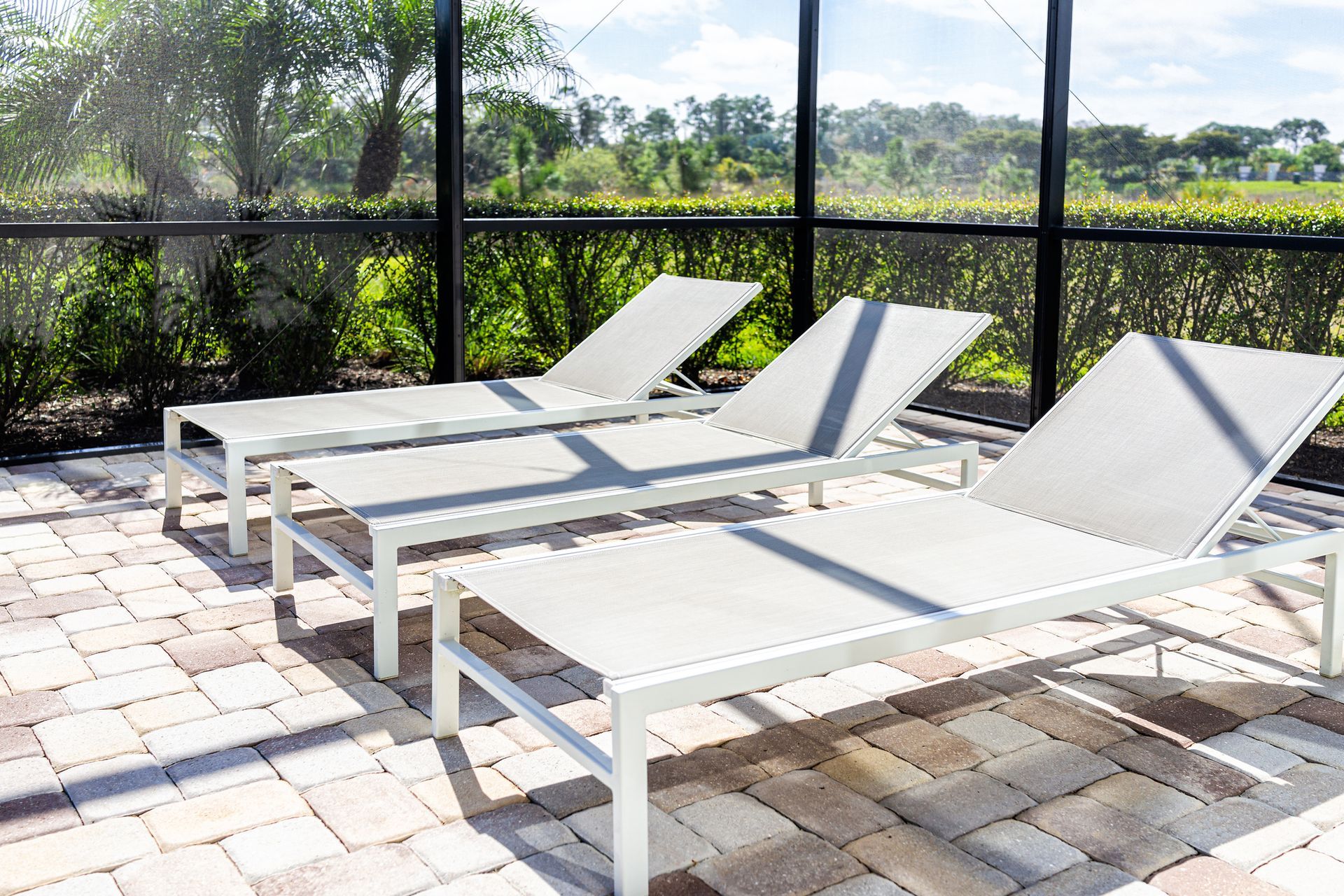 A row of white lounge chairs are sitting on a brick patio.