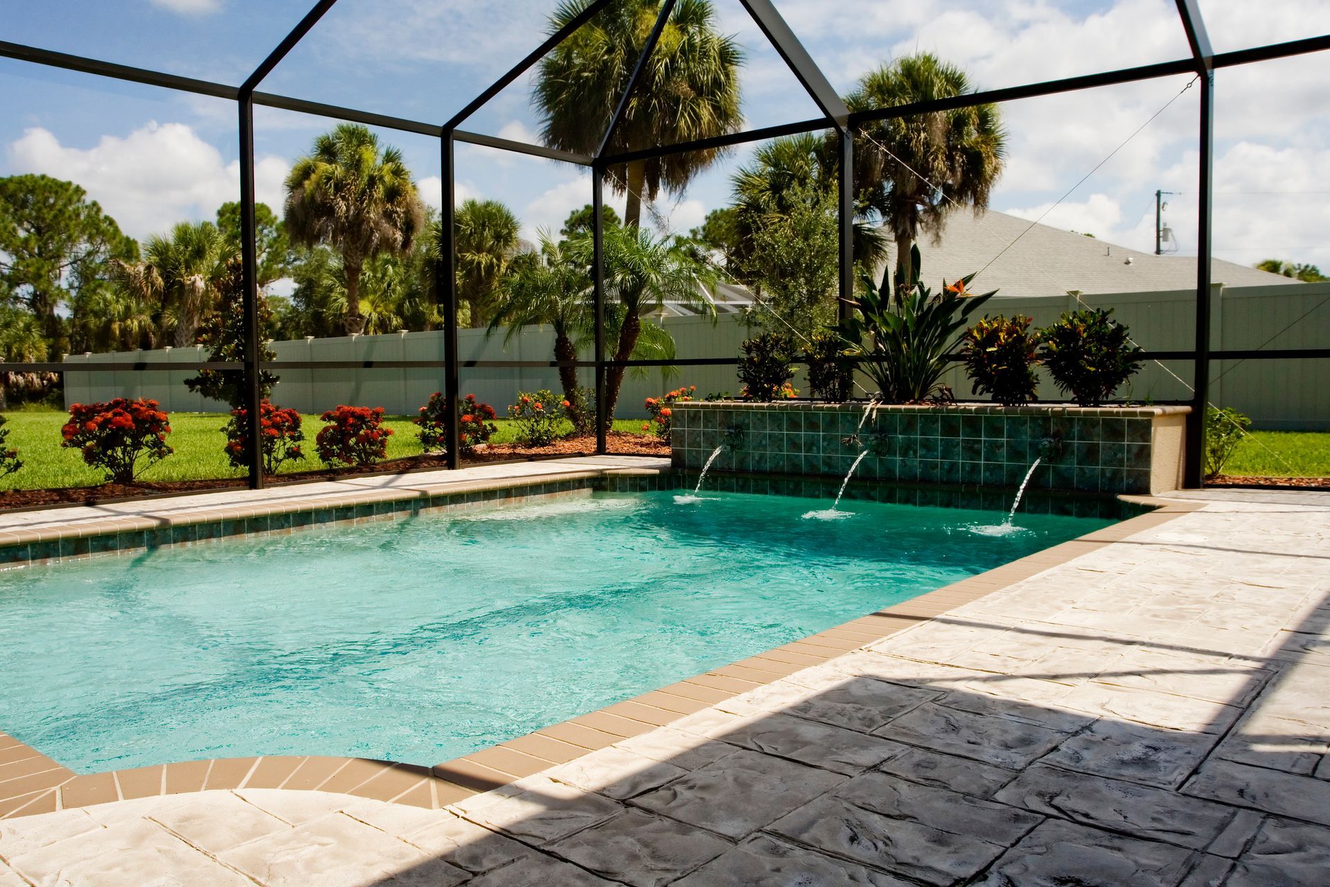 A screened in swimming pool with palm trees in the background