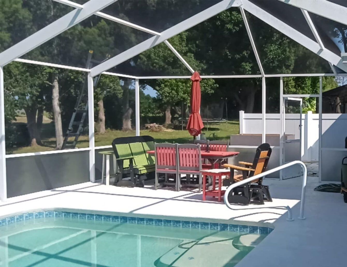 A swimming pool with a screened in area with chairs tables and umbrellas