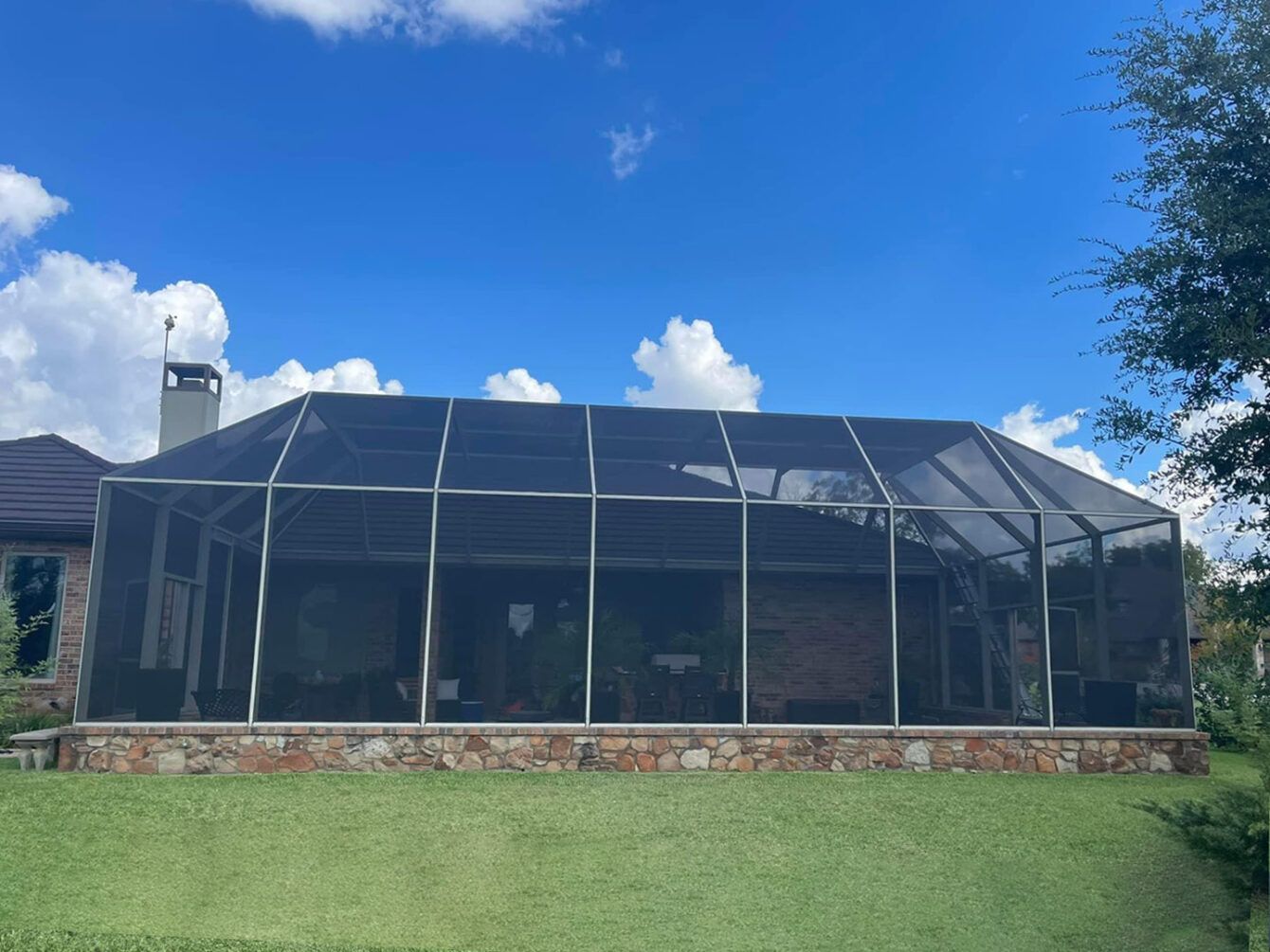 A large screened in porch with a blue sky in the background.