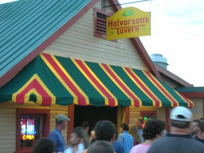 A sign for halverson 's tavern hangs above a crowd of people