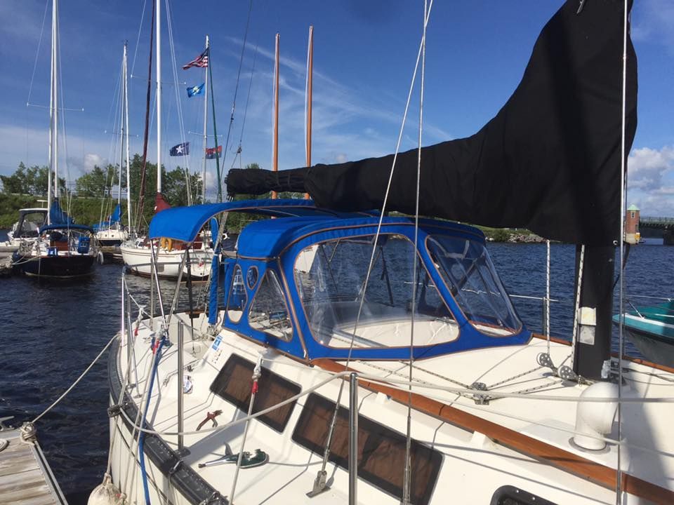 A sailboat with a blue canopy is docked at a marina.