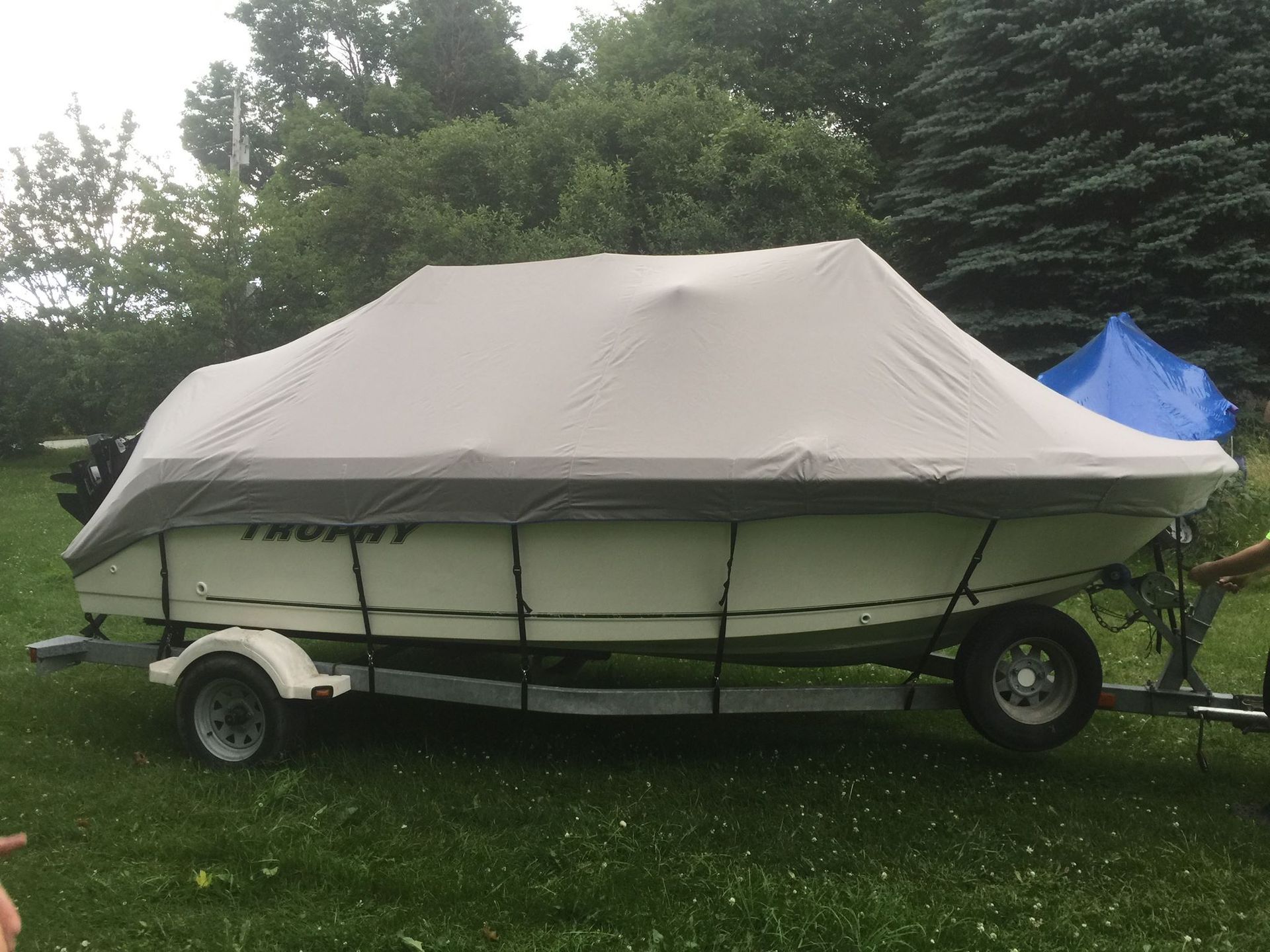 A boat with a cover on it is parked in the grass.