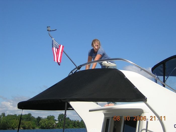 A woman stands on top of a boat with an american flag