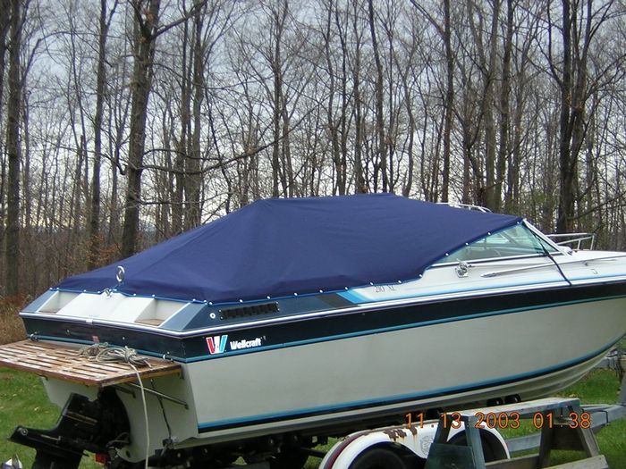 A boat with a blue cover on it is on a trailer