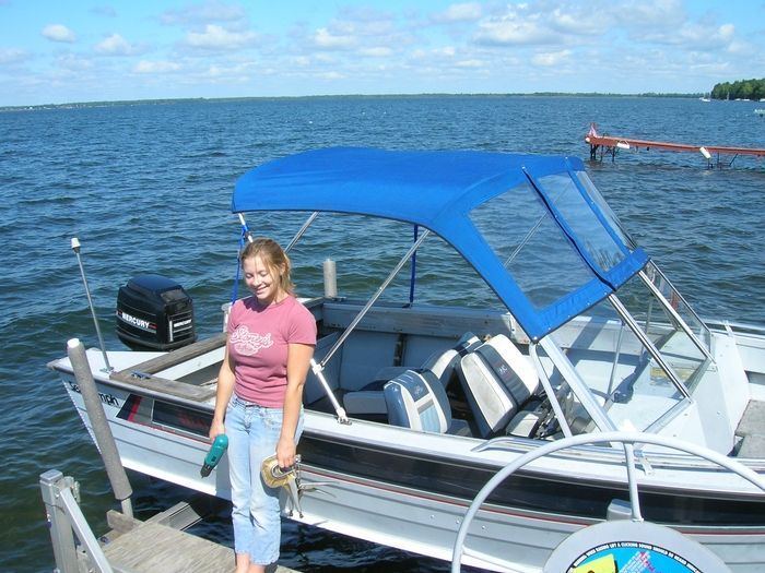 A woman is standing next to a boat with a blue canopy