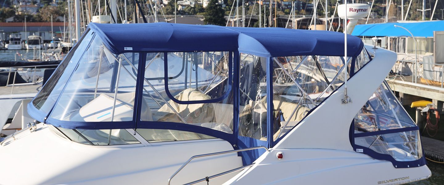 A white boat with a blue canopy is docked at a marina.