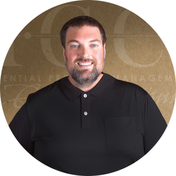 Man with beard in a black polo shirt, smiling, against a neutral background.