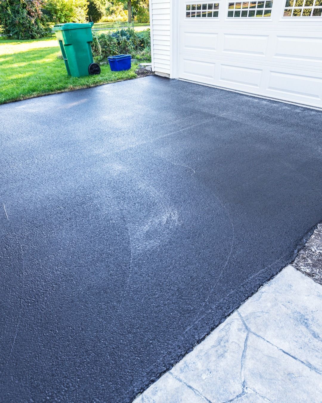 A black asphalt driveway next to a white garage door.