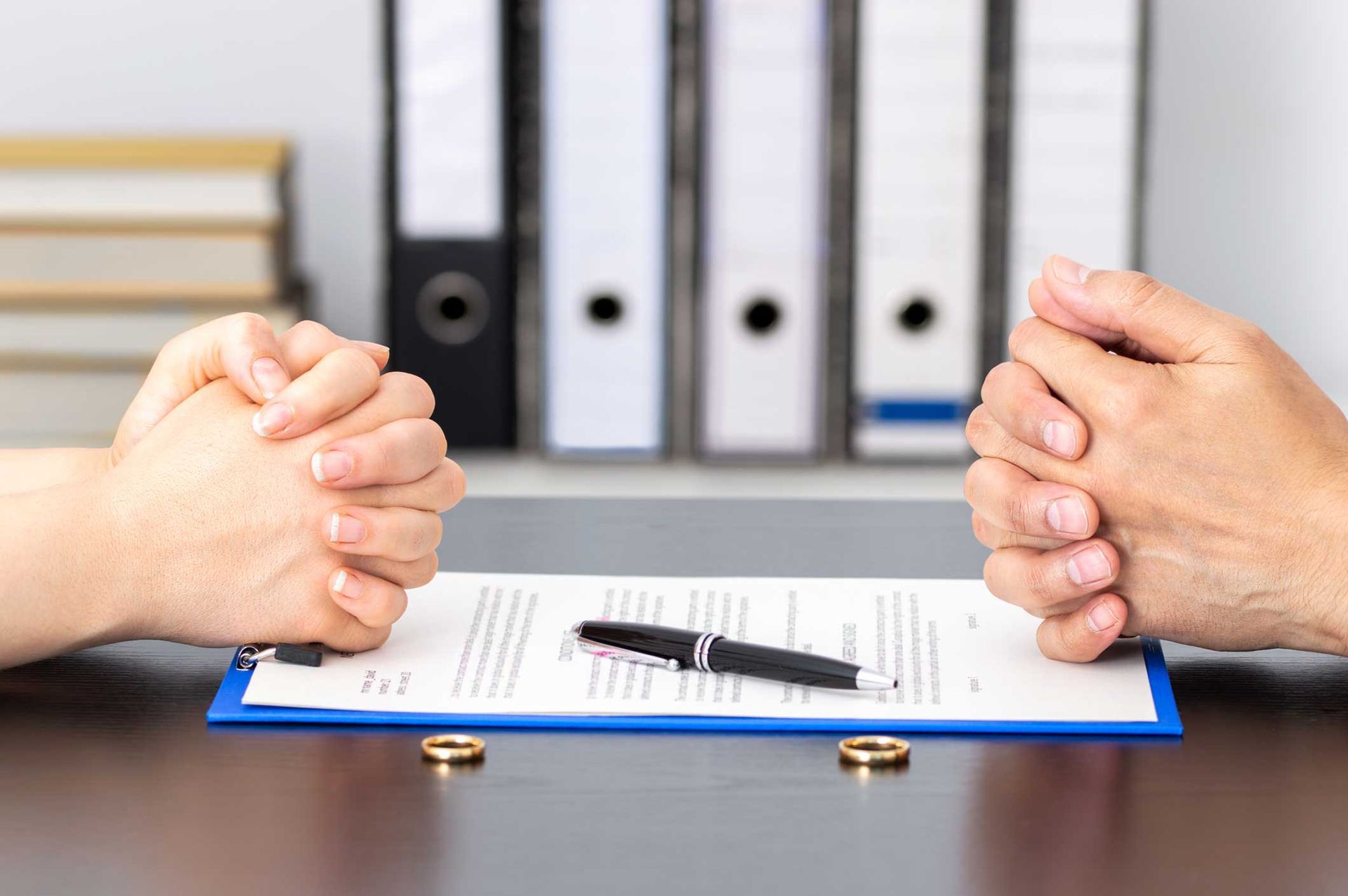 Hands of wife and husband signing divorce documents or premarital agreement at the lawyer's office.