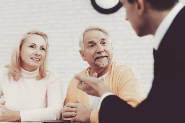 An older couple is sitting at a table talking to a man in a suit.
