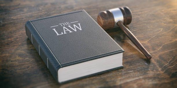 A law book and a judge 's gavel on a wooden table.