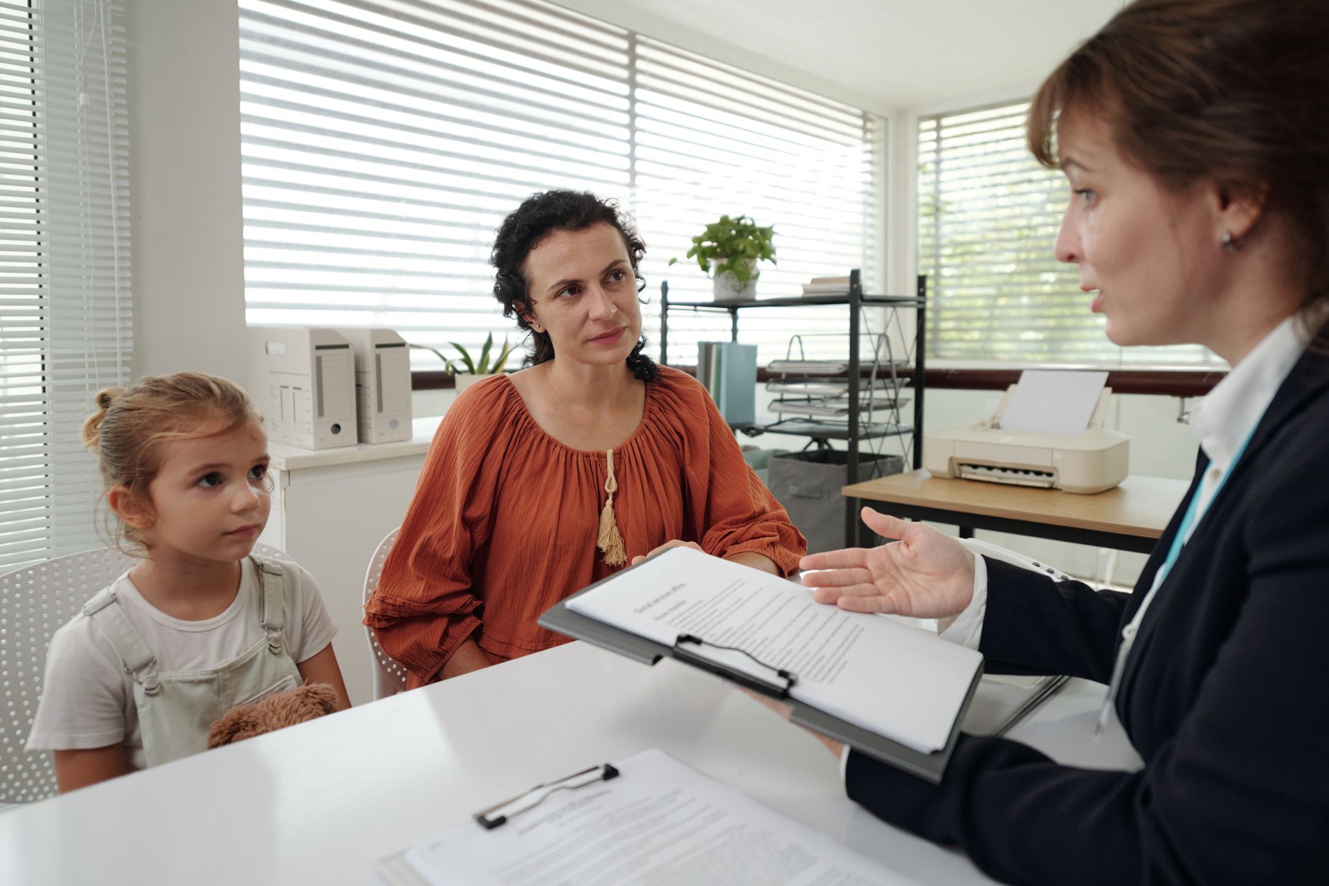 A child custody attorney explains documents to their client with their daughter sitting next to her.