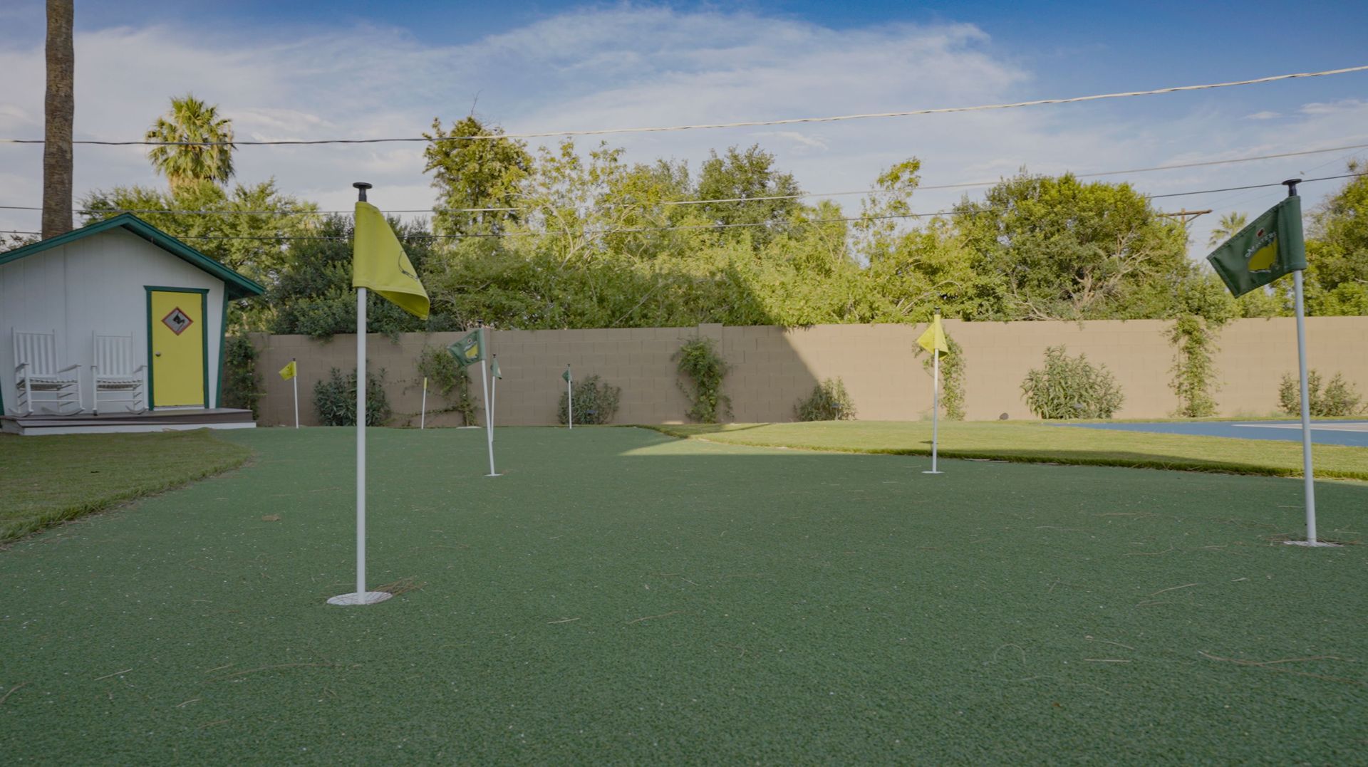 A putting green in a backyard with a house in the background.