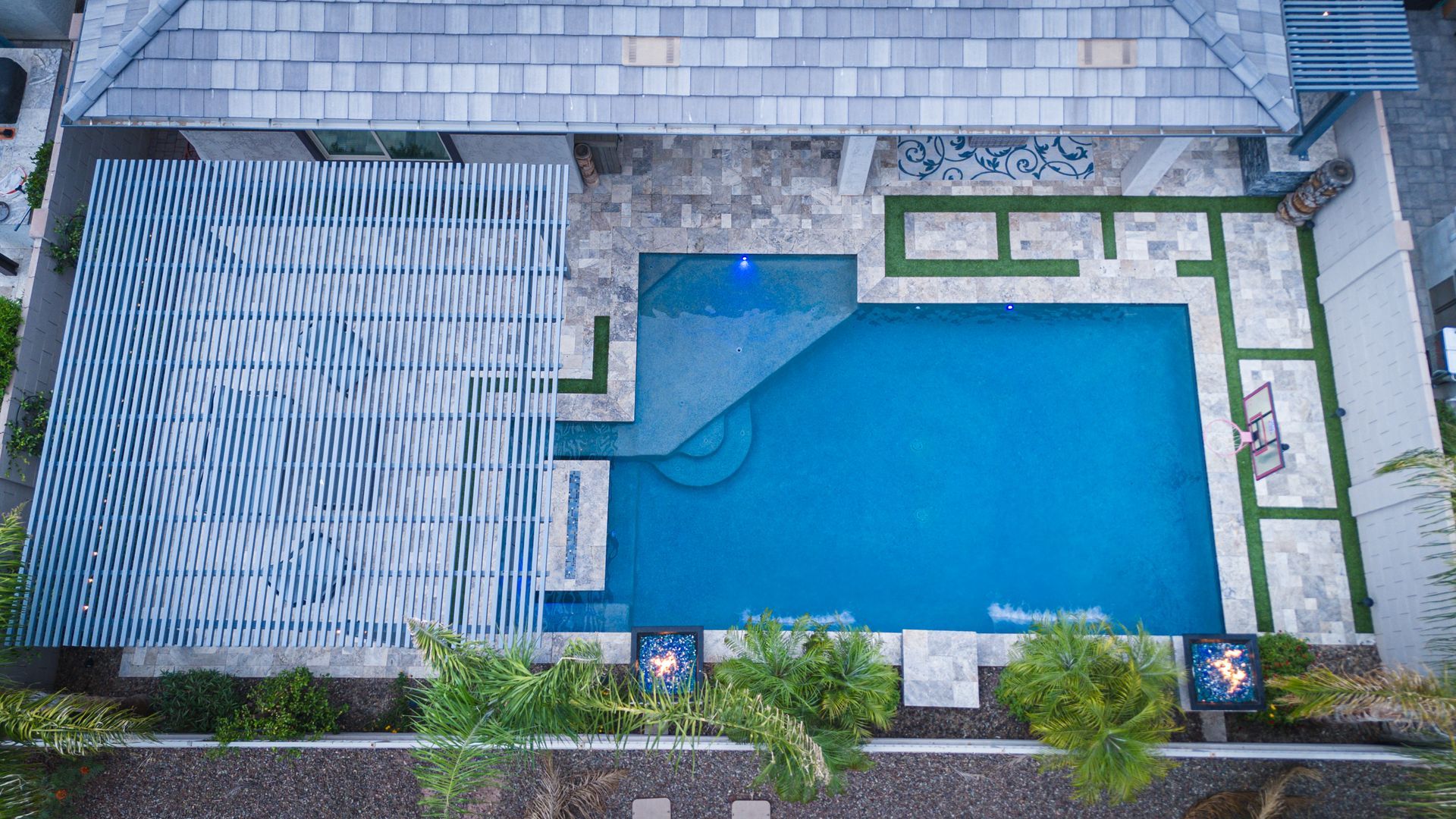 An aerial view of a large swimming pool in the backyard of a house.