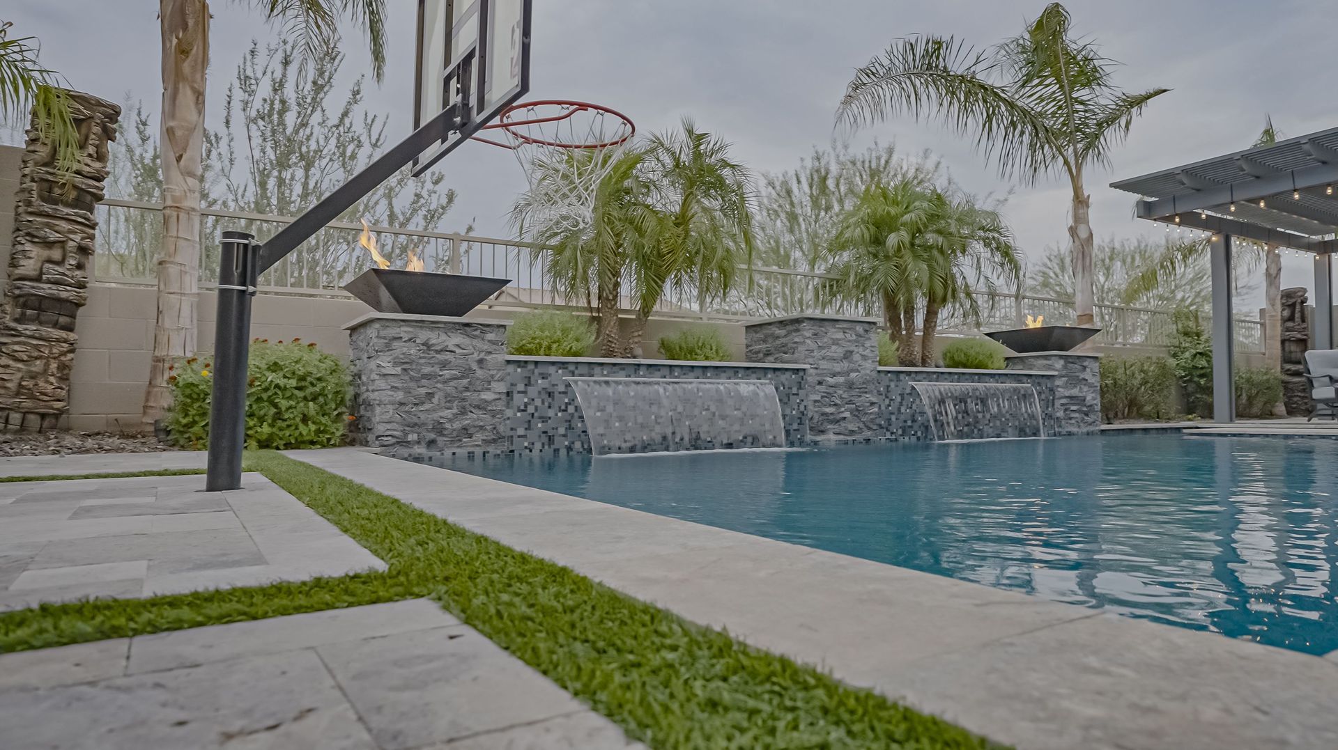A basketball hoop is sitting next to a swimming pool in a backyard.