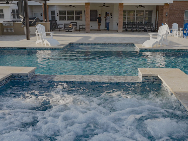 A large swimming pool with a hot tub in the middle