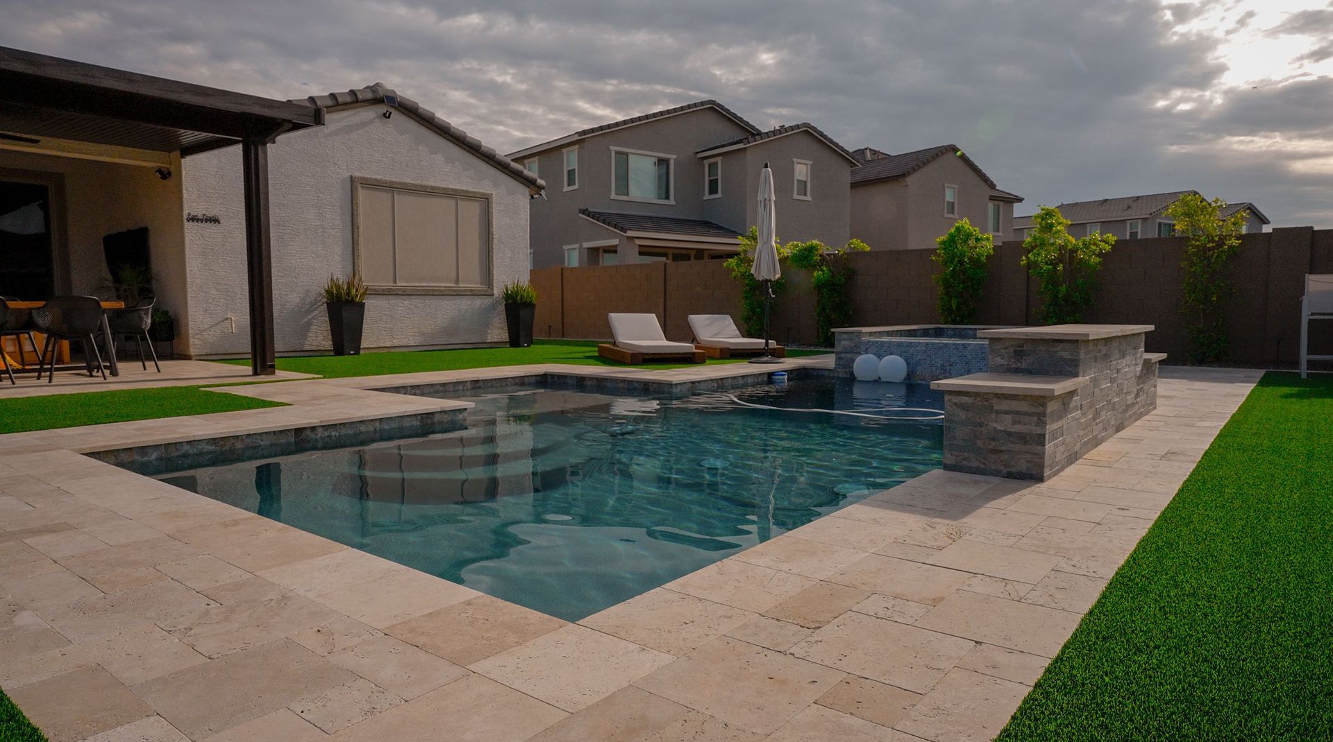 There is a large swimming pool in the backyard of a house.