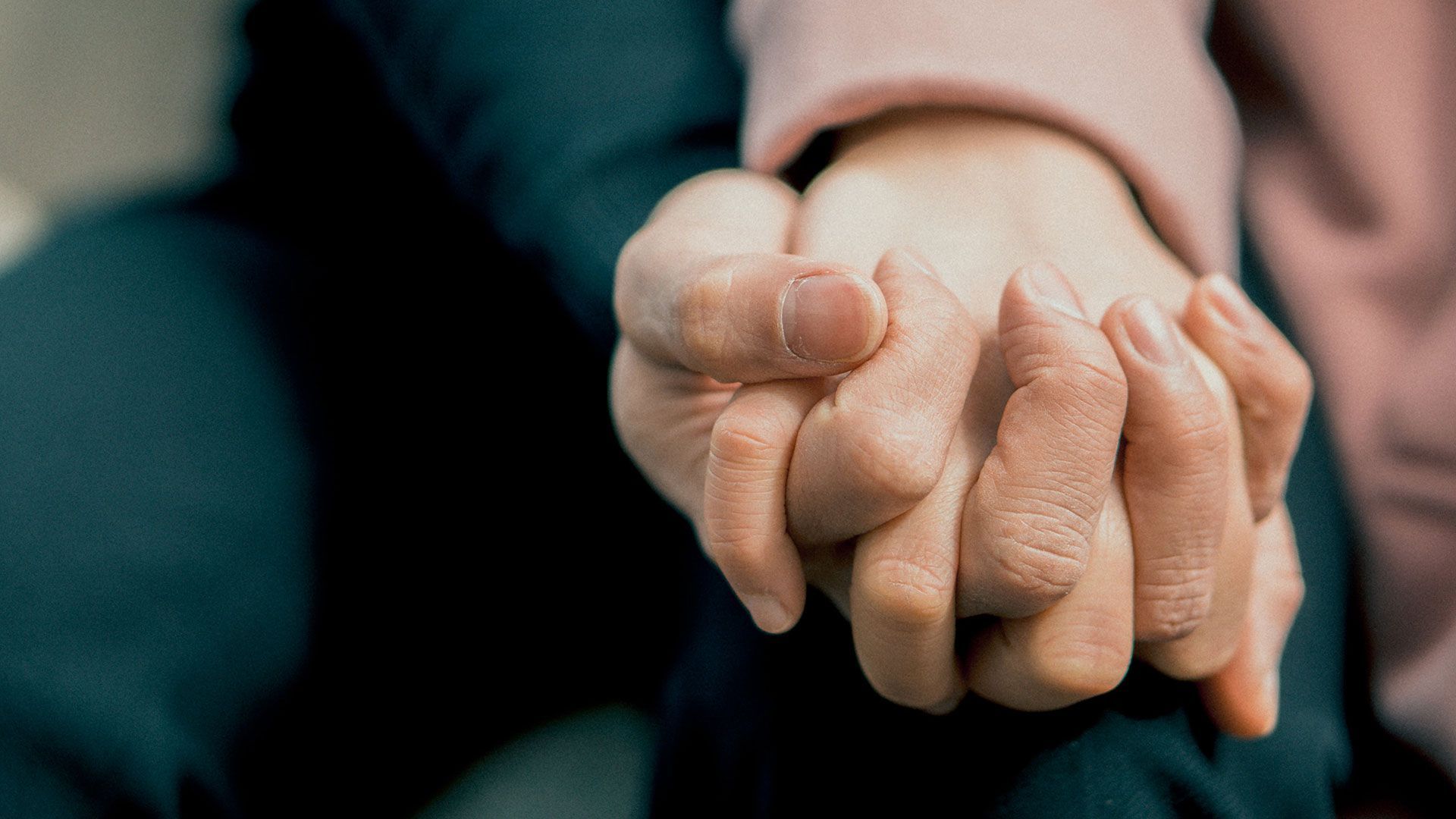 A close up of a person holding another person 's hand.