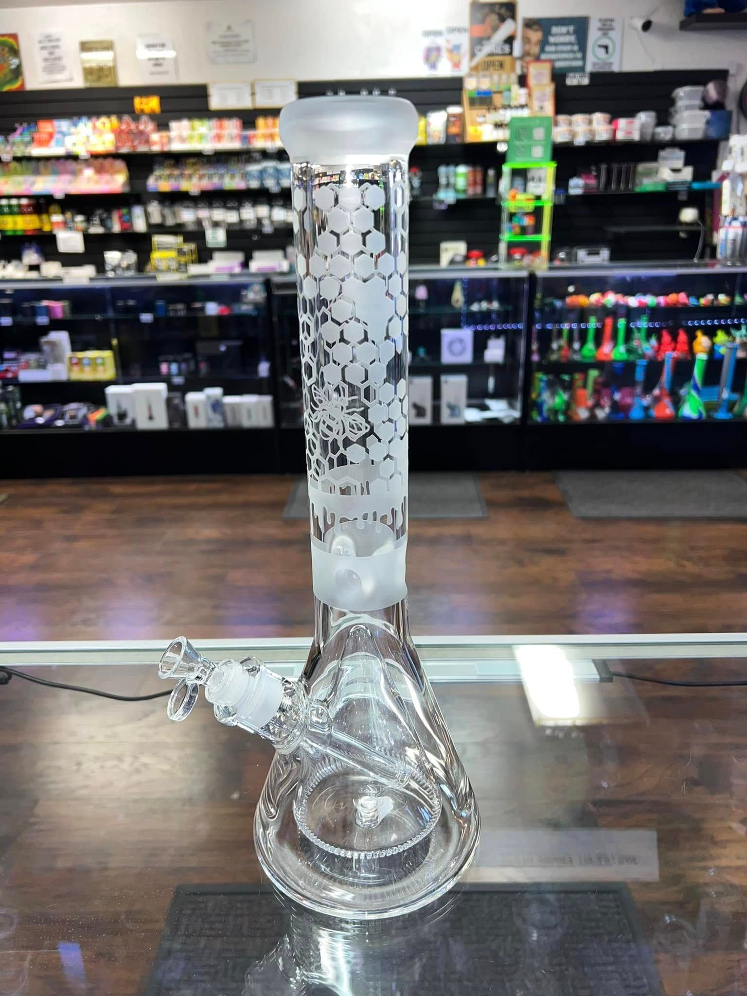 A glass bong is sitting on a glass table in a store.