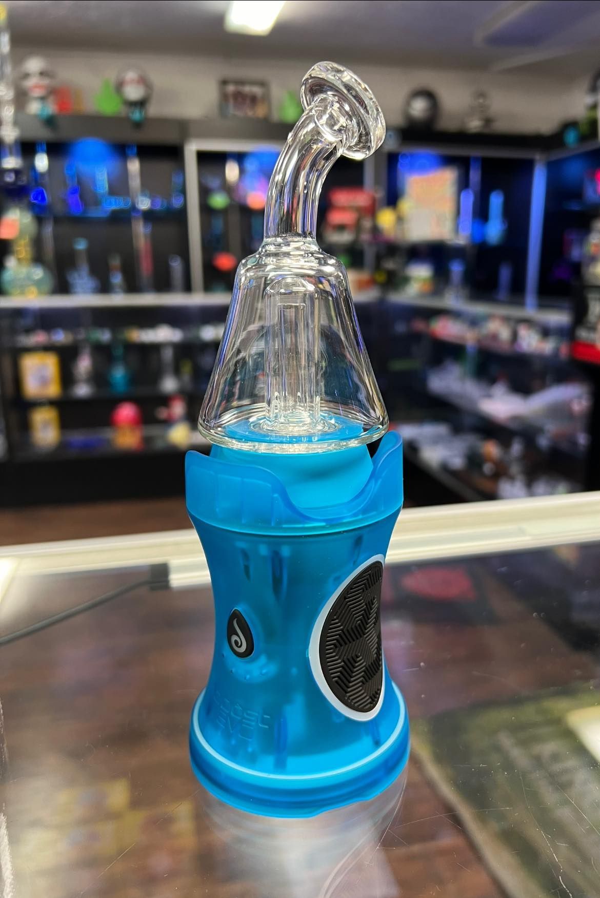 A blue glass pipe is sitting on a glass shelf in a store.