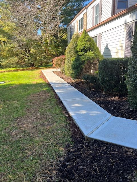 A concrete walkway is leading to a house.