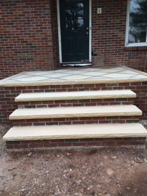A brick porch with white steps and a black door