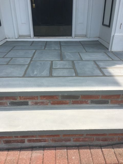 A front porch with brick steps and a stone floor.