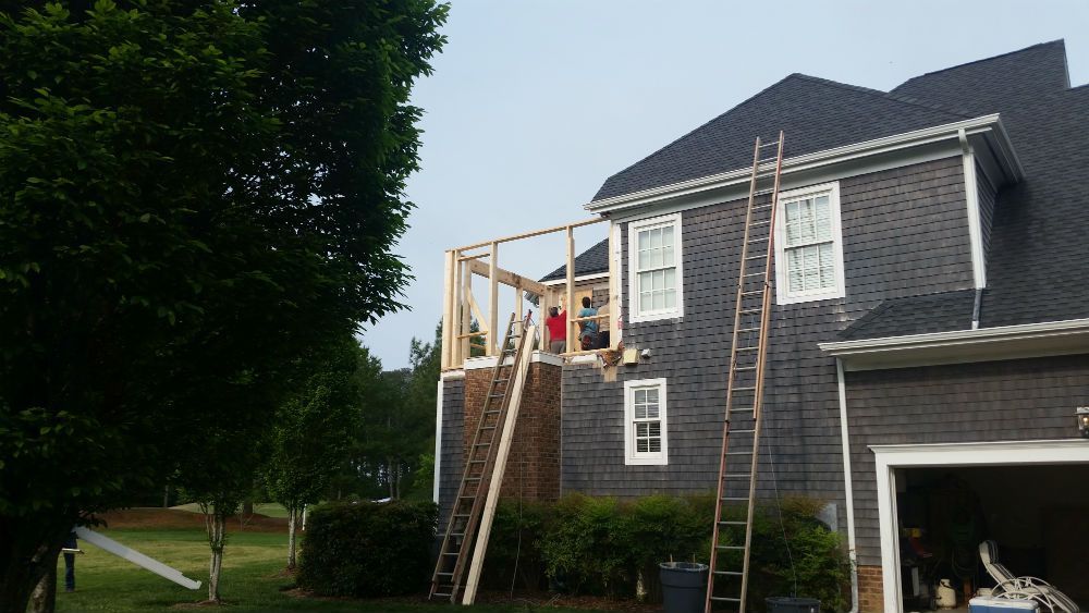 A house is being remodeled with a roof extension being built on top of it.