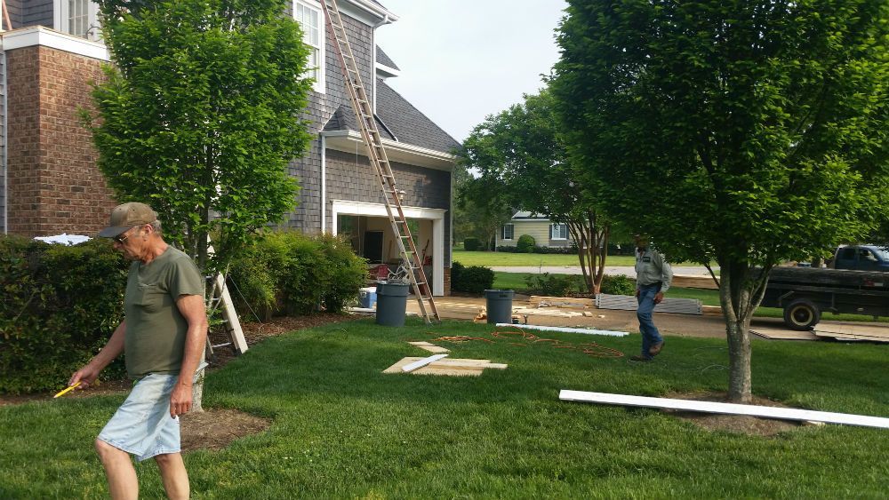 A man is walking in the grass in front of a house.