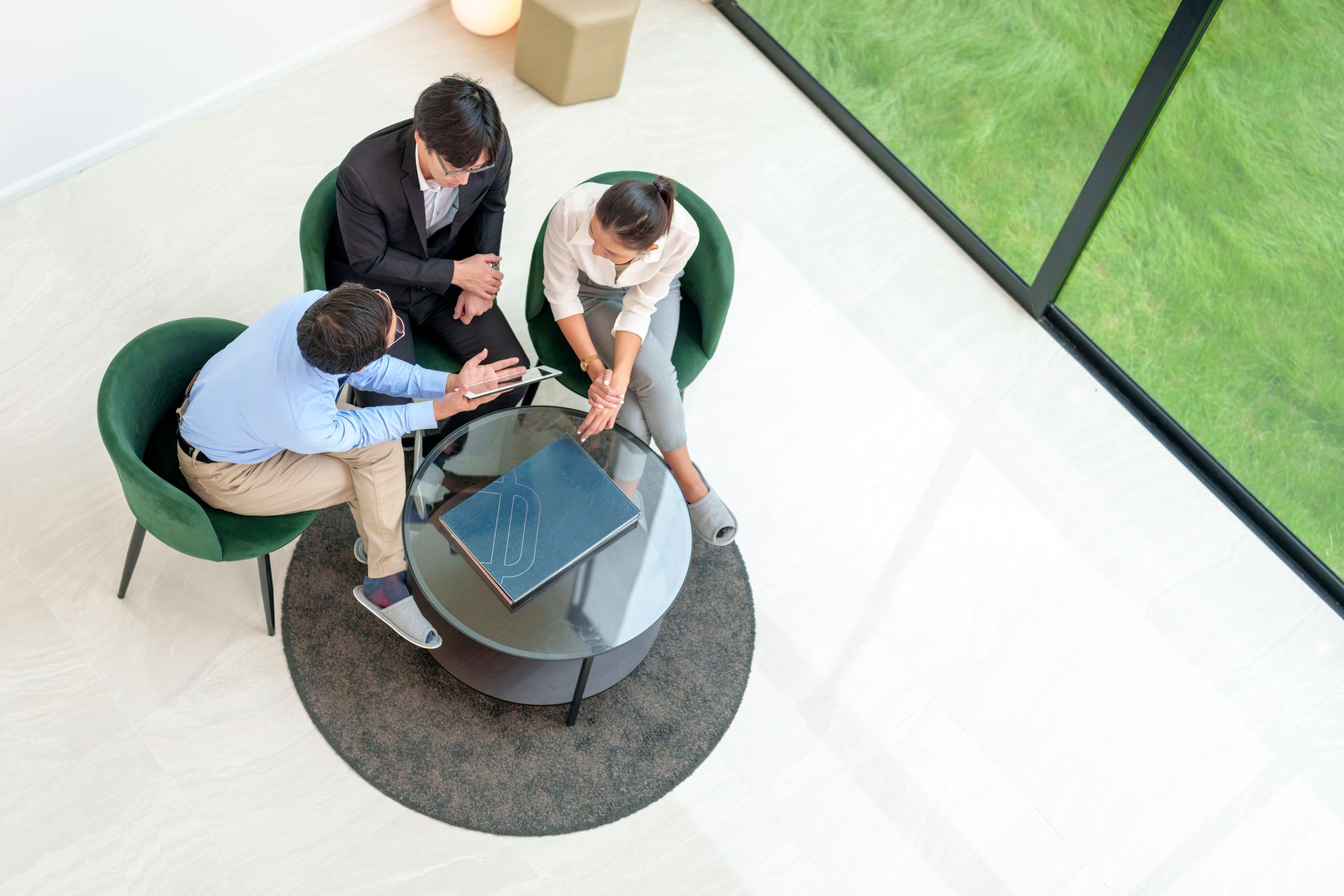 Three people in a business meeting around a table. Laptop on the table, modern office setting.