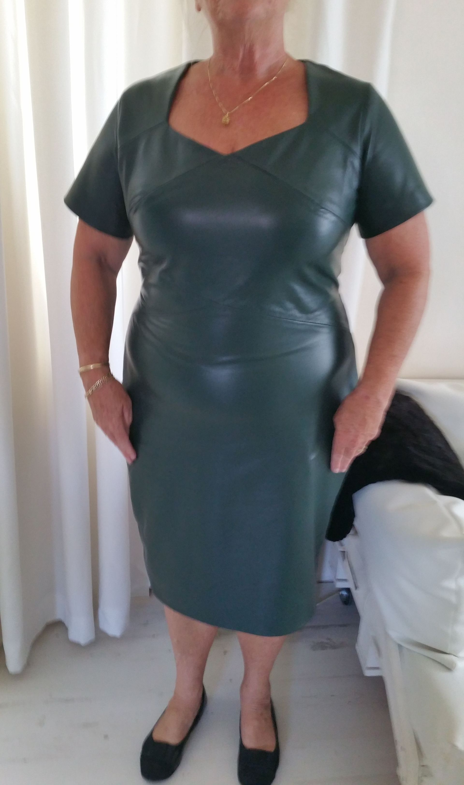 Een vrouw draagt ​​een groene leren jurk grote maat