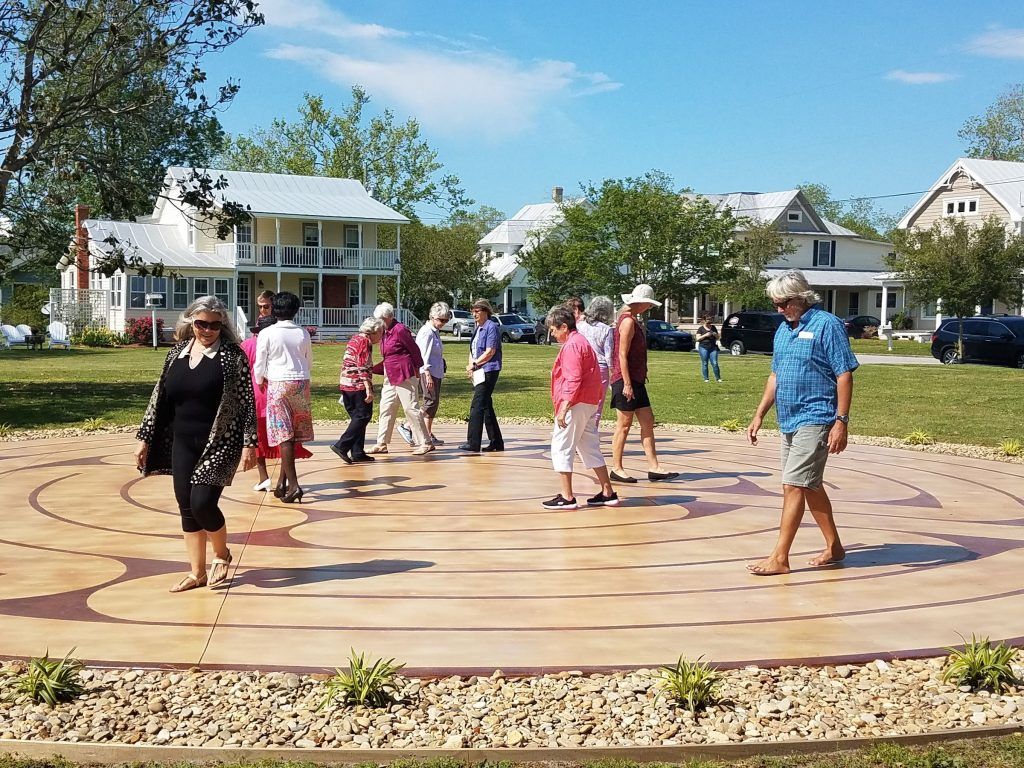 People walking a circular path outdoors; houses in background.