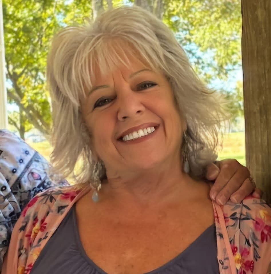 Woman with gray hair smiles, wearing a floral kimono.