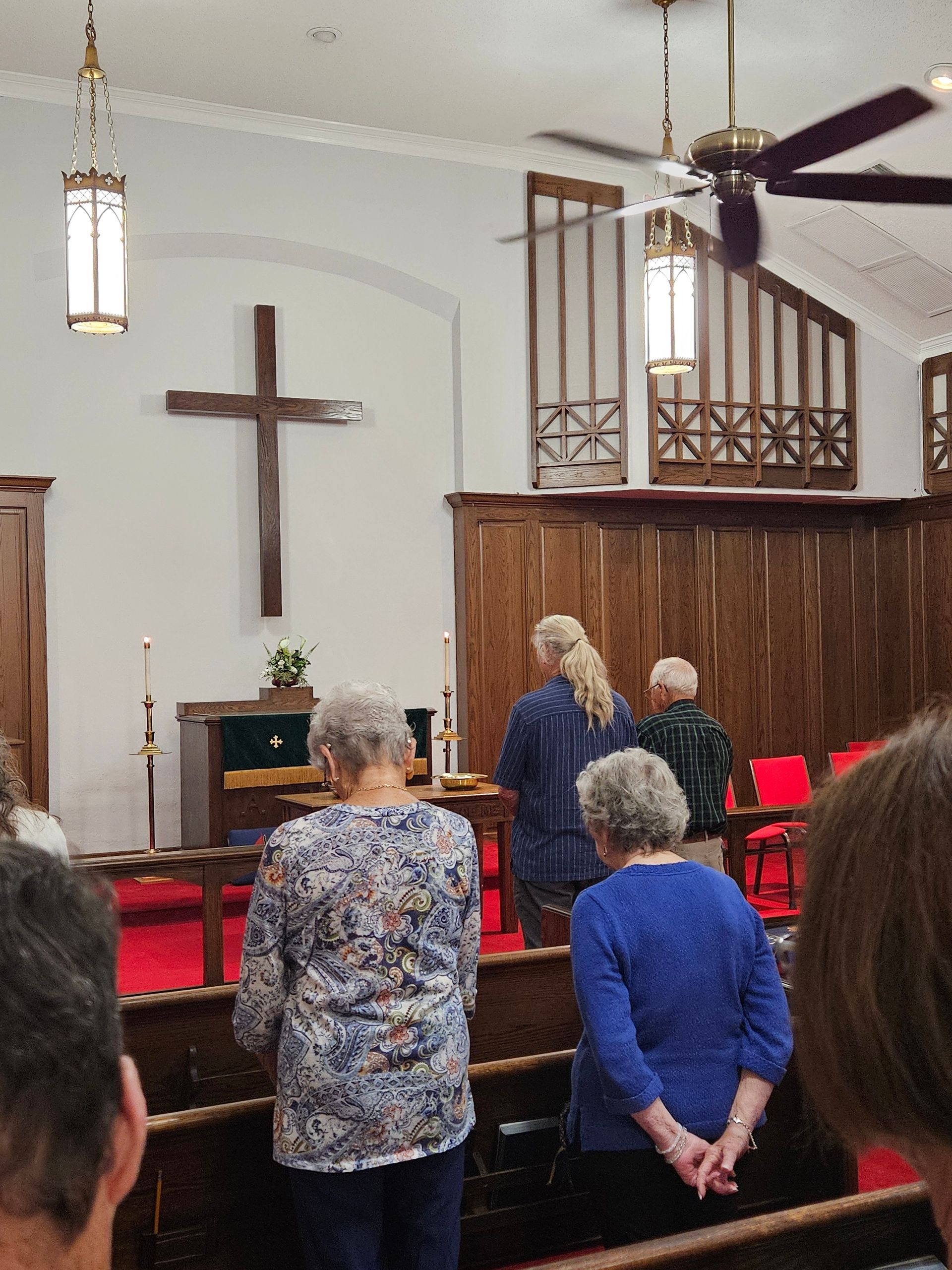 Woman comforts older woman outdoors, holding hands; sunlight.
