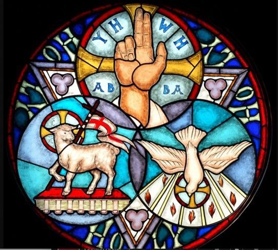 Stained glass window depicting the Holy Trinity: hand, dove, lamb, and Hebrew letters 
